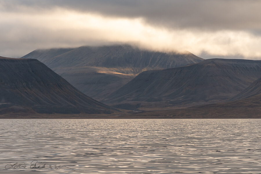 Svalbard_seaview_mountains_clouds_sunlit_spot_mountainside900