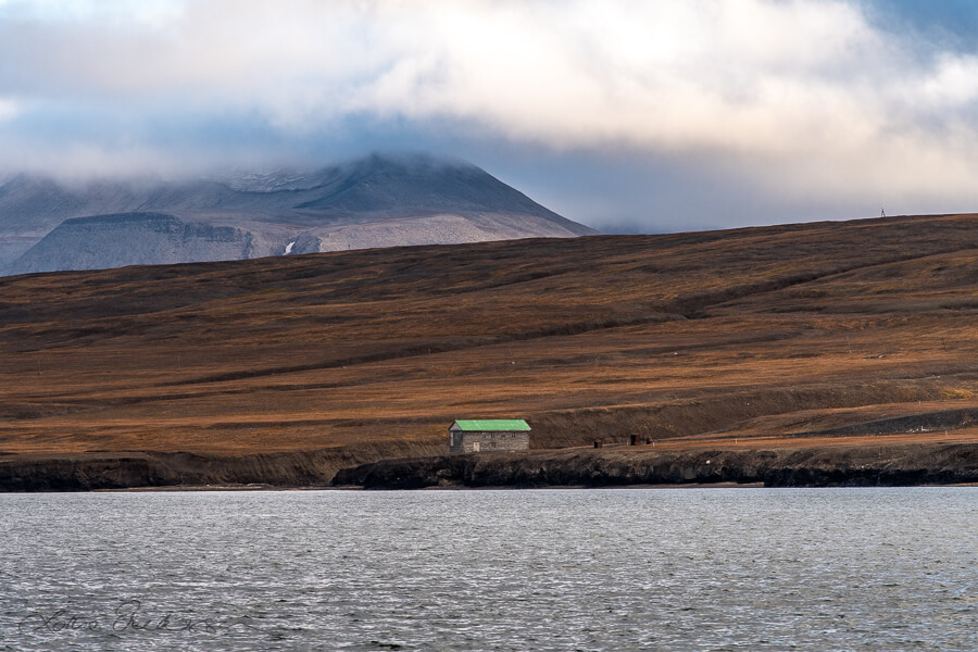 Svalbard_seaview_shore_house_green_roof_mountains_clouds900