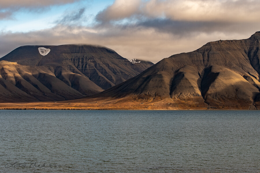 Svalbard_typical_Adventsfjorden_mountains_cabins_clouds